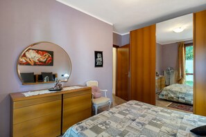 Un dormitorio con cama, cómoda, espejo y una puerta que da a otra habitación.