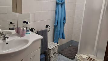 Une salle de bain équipée d’un lavabo, d’un miroir, d’un porte-peignoir et d’un espace douche.