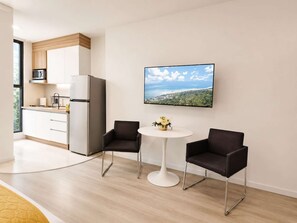 A modern kitchen with a refrigerator, microwave, and a dining area with two chairs and a table. - Coco 1&2 · Two suites with terrace in Condesa · 2 baths (Ciudad de México)