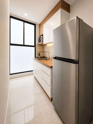 A modern kitchen with a stainless steel refrigerator, wooden countertop, and white cabinetry. - Coco 1&2 · Two suites with terrace in Condesa · 2 baths (Ciudad de México)