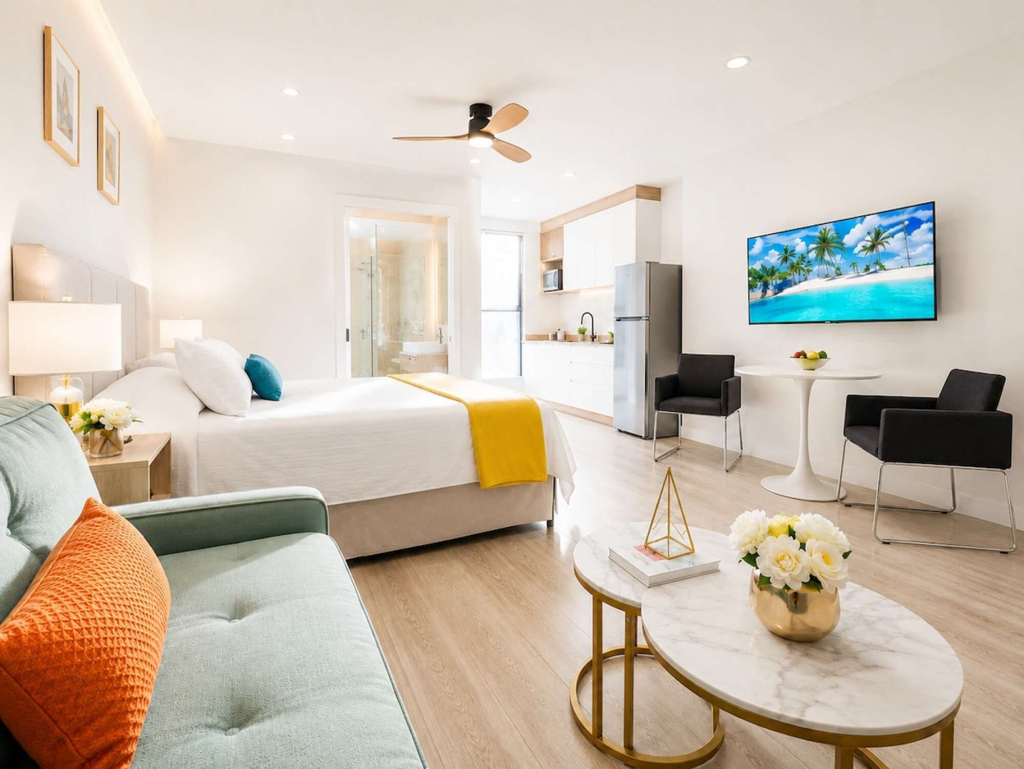 Ein modernes Hotelzimmer mit Bett, Sofa, Esstisch und Fernseher.