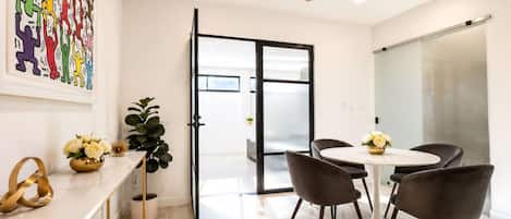A modern office space with a round table, black chairs, a ceiling fan, and a glass door leading to another room.