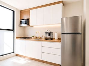A modern kitchen with a built-in microwave, stainless steel refrigerator, and wooden cabinets. - Coco 4&5 · Two suites with terrace in Condesa · 2 baths (Ciudad de México)