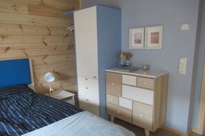 Quarto com cama, penteadeira, espelho e parede com quadros.