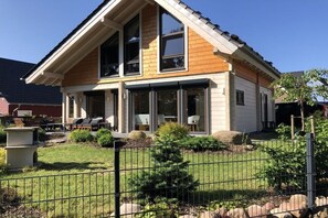 A two-story house with a front porch, large windows, and a fenced yard. - House Seeblick - The Original (Flecken Zechlin)