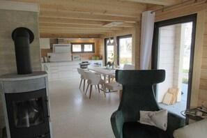 A modern interior with a fireplace, dining area, and large windows. - House Seeblick - The Original (Flecken Zechlin)