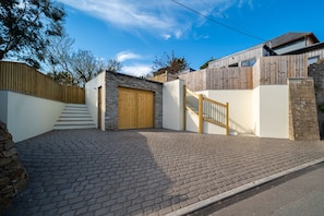 Ein Wohnhaus mit gepflasterter Auffahrt, einer Holztreppe und einer Garage.