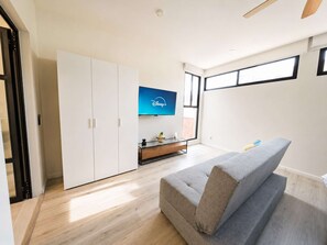 A modern living room with a grey sofa, a flat-screen TV mounted on the wall, and a wooden cabinet. - Coco 7&8 · Two suites with terrace in Condesa · 2 baths (Ciudad de México)