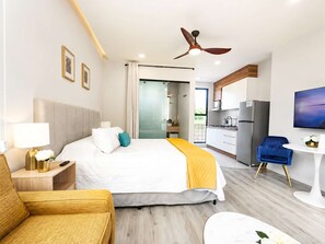 A hotel room with a bed, a desk, a chair, a TV, a ceiling fan, and a kitchen area. - Coco 7&8 · Two suites with terrace in Condesa · 2 baths (Ciudad de México)