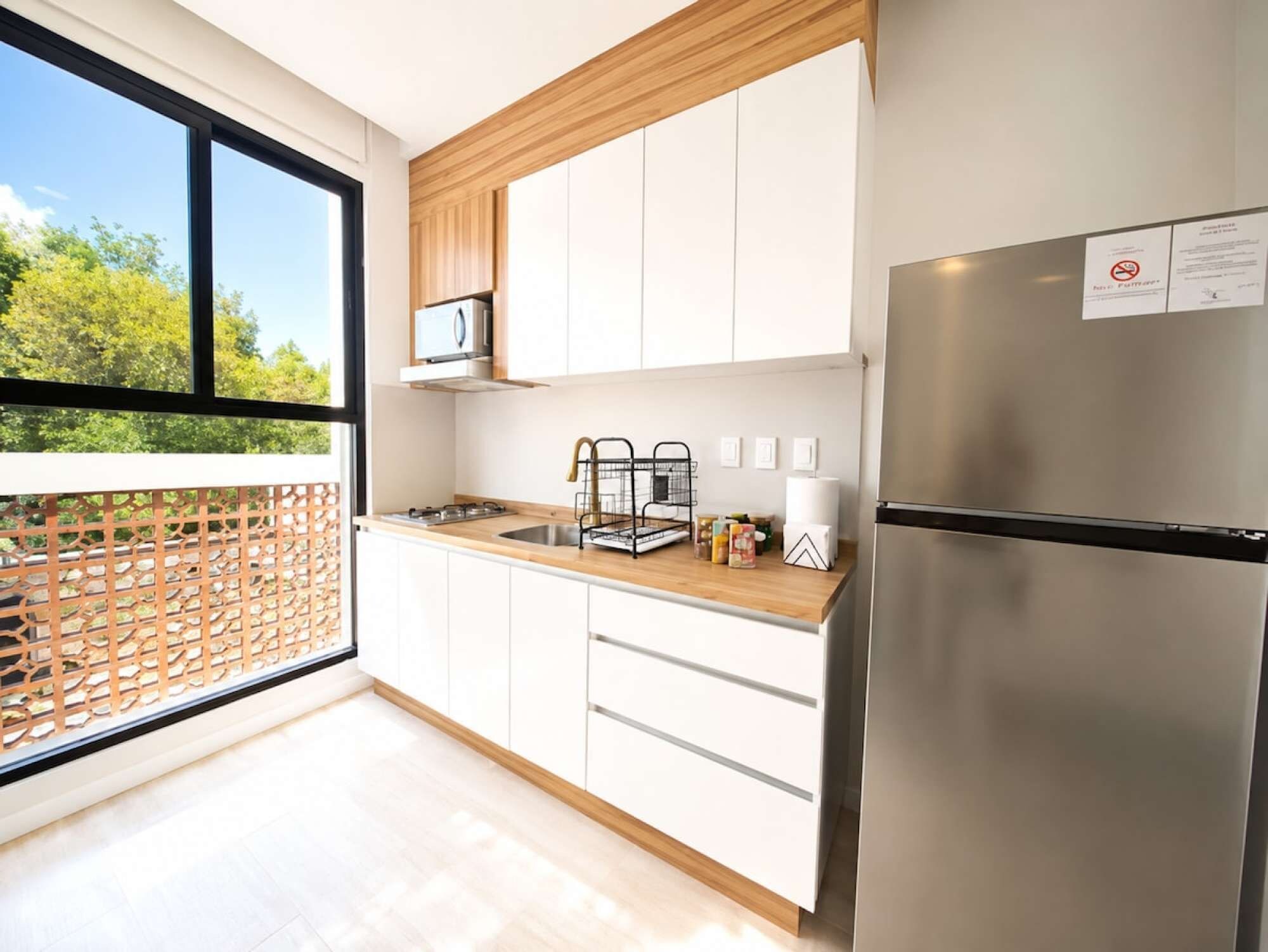 A modern kitchen with white cabinets, a stainless steel refrigerator, and a wooden countertop.