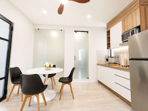 A modern kitchen with a round dining table, black chairs, and a stainless steel refrigerator. - Coco 7&8 · Two suites with terrace in Condesa · 2 baths (Ciudad de México)