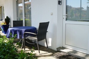 Eine Terrasse mit Tisch und Stühlen, einer Tür und einem Fenster.