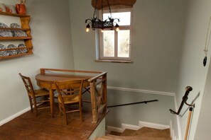 A dining area with a wooden table and chairs, a hanging light fixture, and a window with a view. - Old Forester's Lodge Hohnstein (Hohnstein)