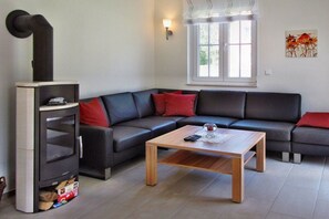 A modern living room with a sectional sofa, a wooden coffee table, and a built-in fireplace. - Holiday home Cormorant (Glowe)
