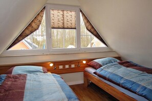 A bedroom with two beds, a sloped ceiling, and a window with a view of the outside. - Holiday home Cormorant (Glowe)