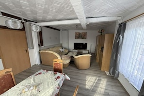 A compact living space with a sofa set, a TV, and a dining table with a floral tablecloth.