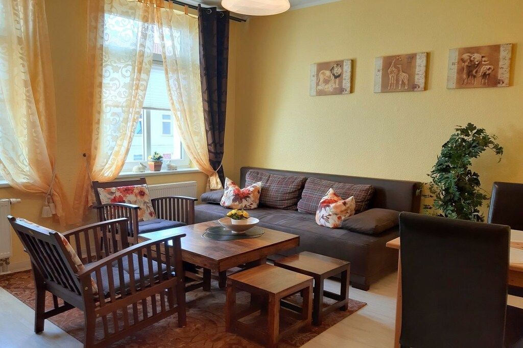 A living room with a sofa, chairs, a coffee table, and a plant.