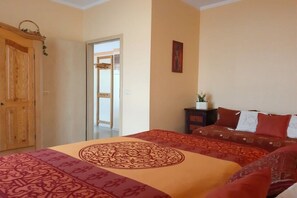 A bedroom with a large bed, a wooden wardrobe, a small bedside table with a plant, and a door leading to another room. - Holiday apartment in Waren with swimming pool (Waren)