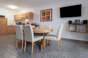 Eine moderne Küche mit Esstisch, Stühlen, einem Fernseher und einer Kaffeemaschine.