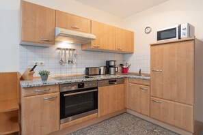 Eine Küche mit Holzschränken, einem Edelstahlbackofen, einer Mikrowelle und einer Kaffeemaschine.