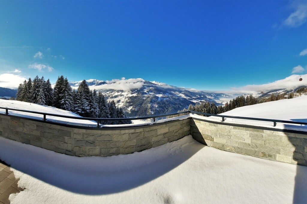A snow-covered landscape with a stone wall and a clear blue sky.