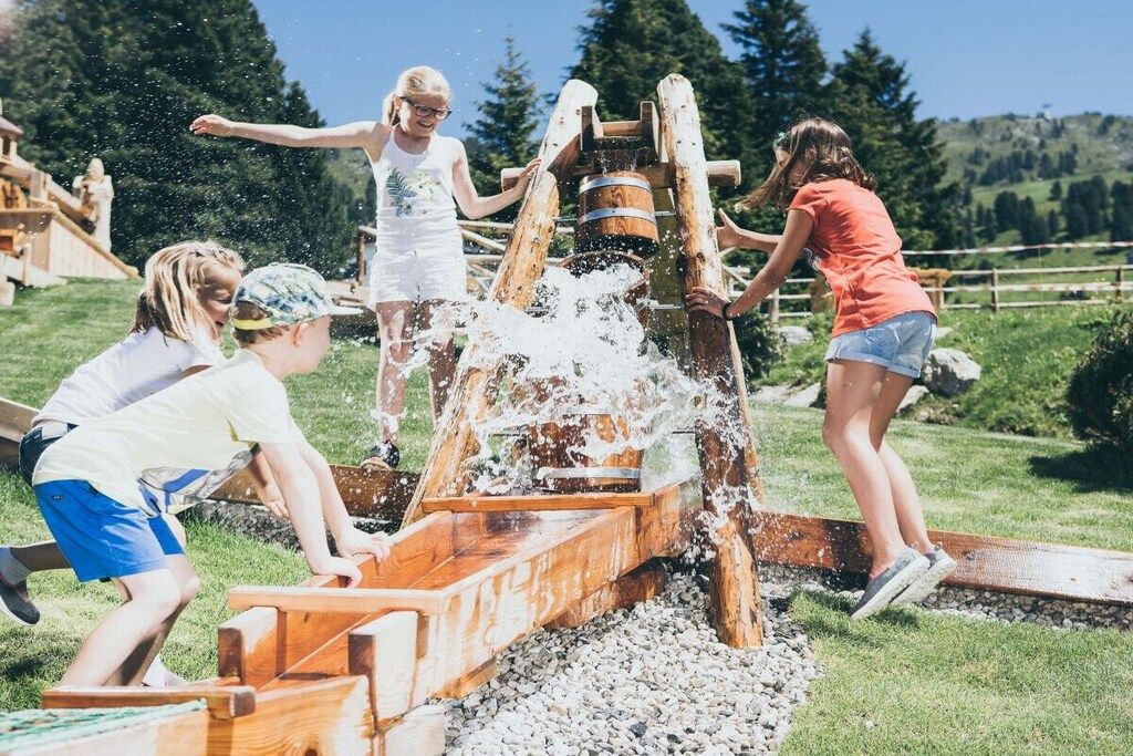 A group of people playing with a water pump in an outdoor setting.