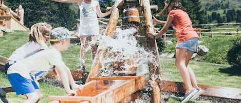 A group of people playing with a water pump in an outdoor setting.