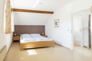 Een slaapkamer met een houten bed, een nachtkastje, een bedlamp, een deur en een plafond met houten balken.