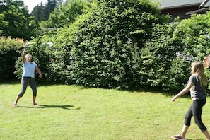 An outdoor area with a grassy lawn and dense foliage in the background. - Located directly on the Drau reservoir (Feistritz i.R.)