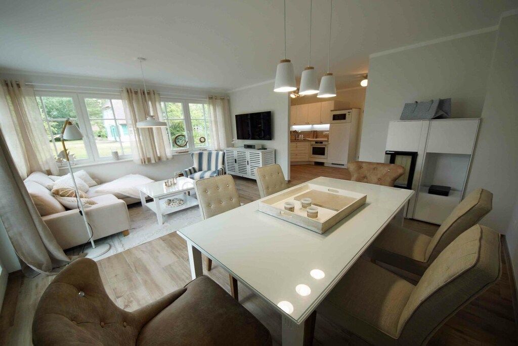 Una sala moderna con comedor, cocina y televisor montado en la pared.