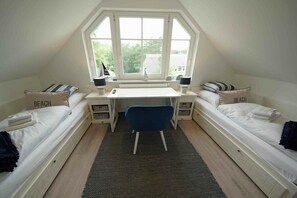 Ein Schlafsaalzimmer mit zwei Einzelbetten, einem Schreibtisch und einem Stuhl.