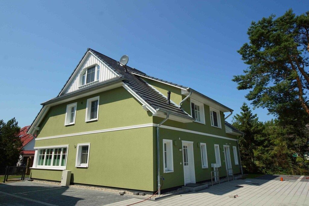 A two-story building with a sloped roof, white trim, and a satellite dish.