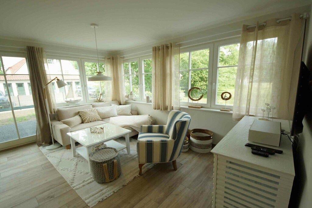 A living room with a sofa, armchair, coffee table, and a television on a stand.