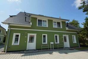 A two-story building with a green exterior, white trim, and a tiled roof. - Holiday home in Prerow with sauna (Prerow)