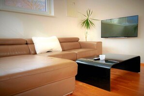 A modern living room with a sofa, a coffee table, and a flat-screen TV mounted on the wall. - Lakeside idyll Winkler II (Bodensdorf)