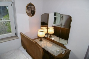 A bedroom with a wooden bed, bedside lamps, a mirror, and a framed photo on the wall. - Holiday home with 1 bedroom (Thale OT Altenbrak)