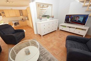 A living room with a TV, two armchairs, a coffee table, and a white dresser. - Holiday apartment with 2 bedrooms (Prerow)