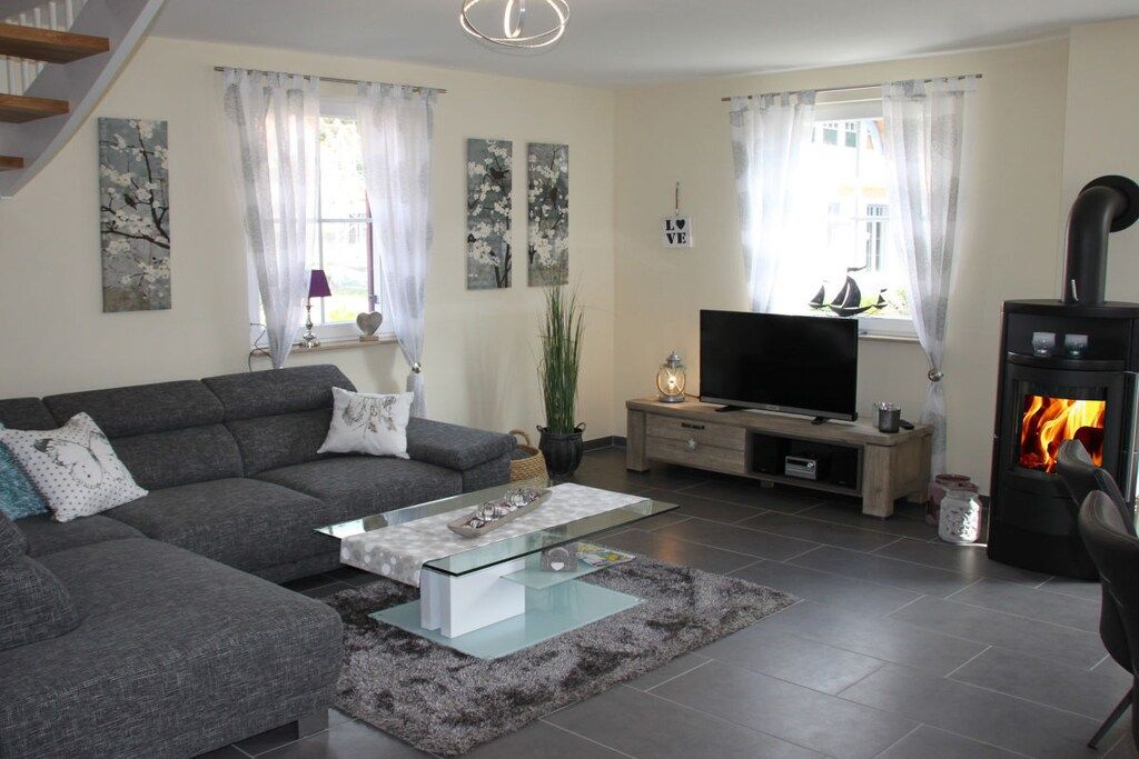 A modern living room with a sofa, a glass coffee table, a flat-screen TV, a fireplace, and artwork on the walls.
