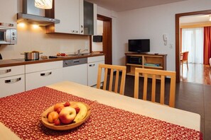 Eine moderne Küche mit Essbereich, einem Fernseher und einer rot gemusterten Tischdecke.