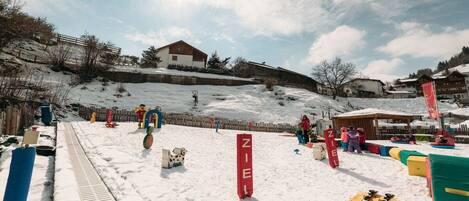 A snowy ski slope with a wooden fence, a sled, and a ski lift in the background.