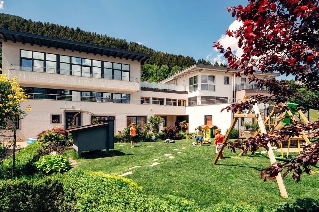 Un edificio moderno con varios pisos, un césped bien cuidado y una zona de juegos.