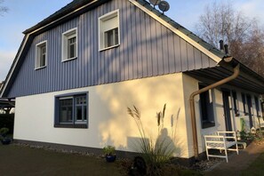 Ein zweigeschossiges Haus mit einem geneigten Dach, einer Satellitenschüssel und einem sichtbaren Schornstein.