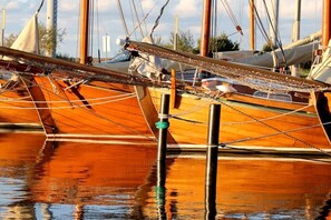 Ein hölzernes Boot liegt in einer Marina, im Hintergrund sind weitere Boote sichtbar.