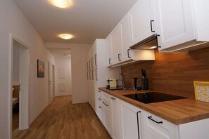 A kitchen with white cabinets, a wooden countertop, and a black stove.