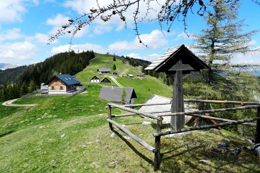 A rural village with traditional wooden houses, a wooden fence, and a clear view of the surrounding hills.