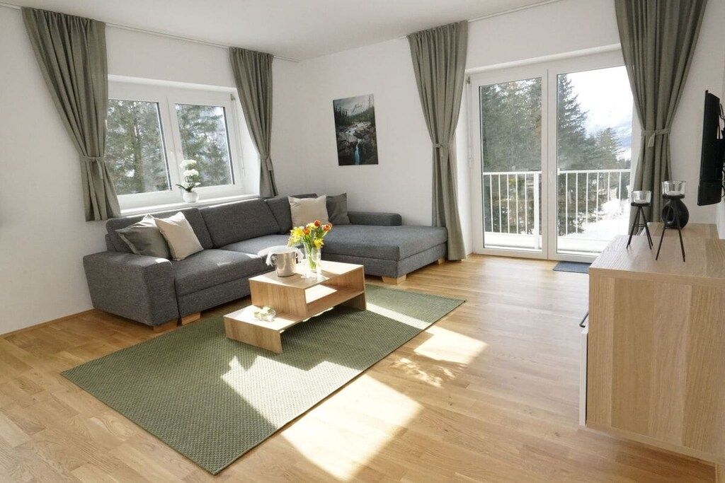 Una sala de estar moderna con un sofá gris, una mesa de centro de madera y un tapete verde.