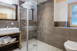 A modern bathroom with a glass-enclosed shower, a white sink, and a toilet.