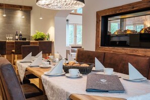 A dining area with tables set for a meal, a chandelier, and a view of the outdoors.