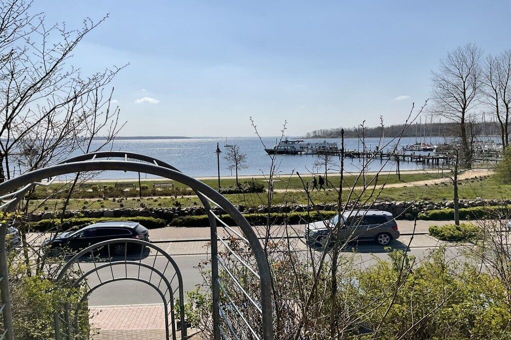 A parking area with vehicles, a waterfront view, and a dock with boats.