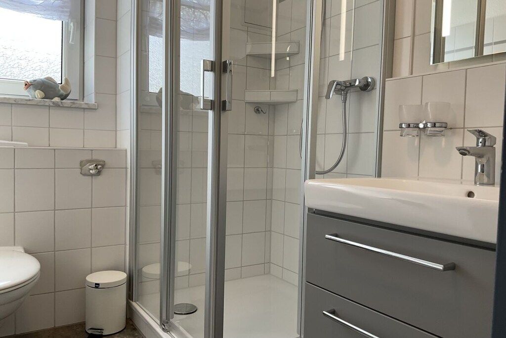 Une salle de bain moderne avec une douche à parois de verre, des toilettes et un meuble-lavabo avec un miroir.